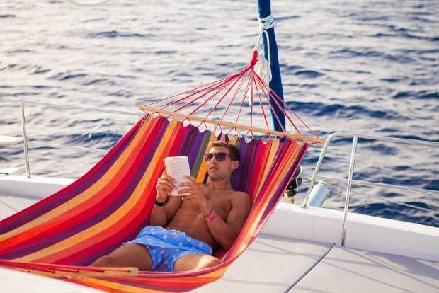 Man reading a book on a hammock on a healthy holiday on a yacht