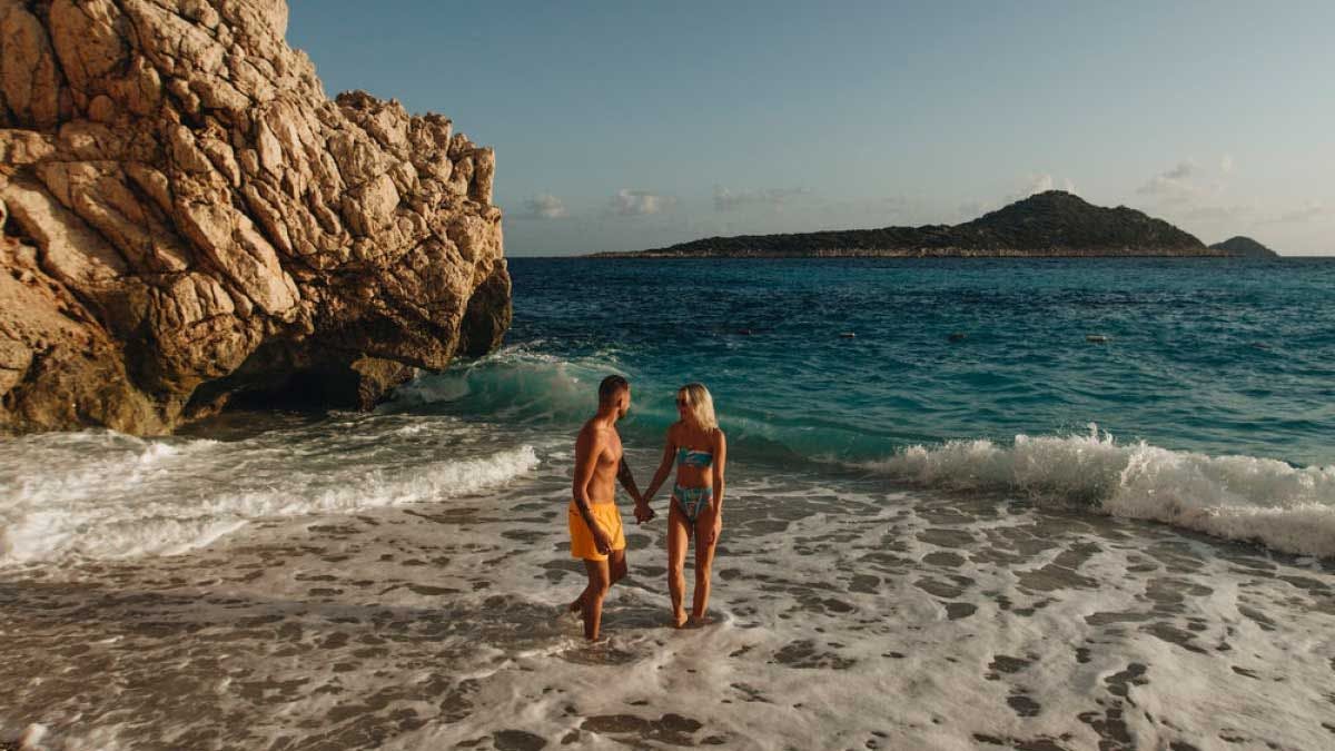 Couple walk in the waves on beach in Turkey