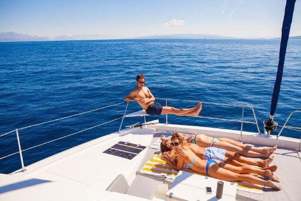 Group sunbathe on bow of catamaran