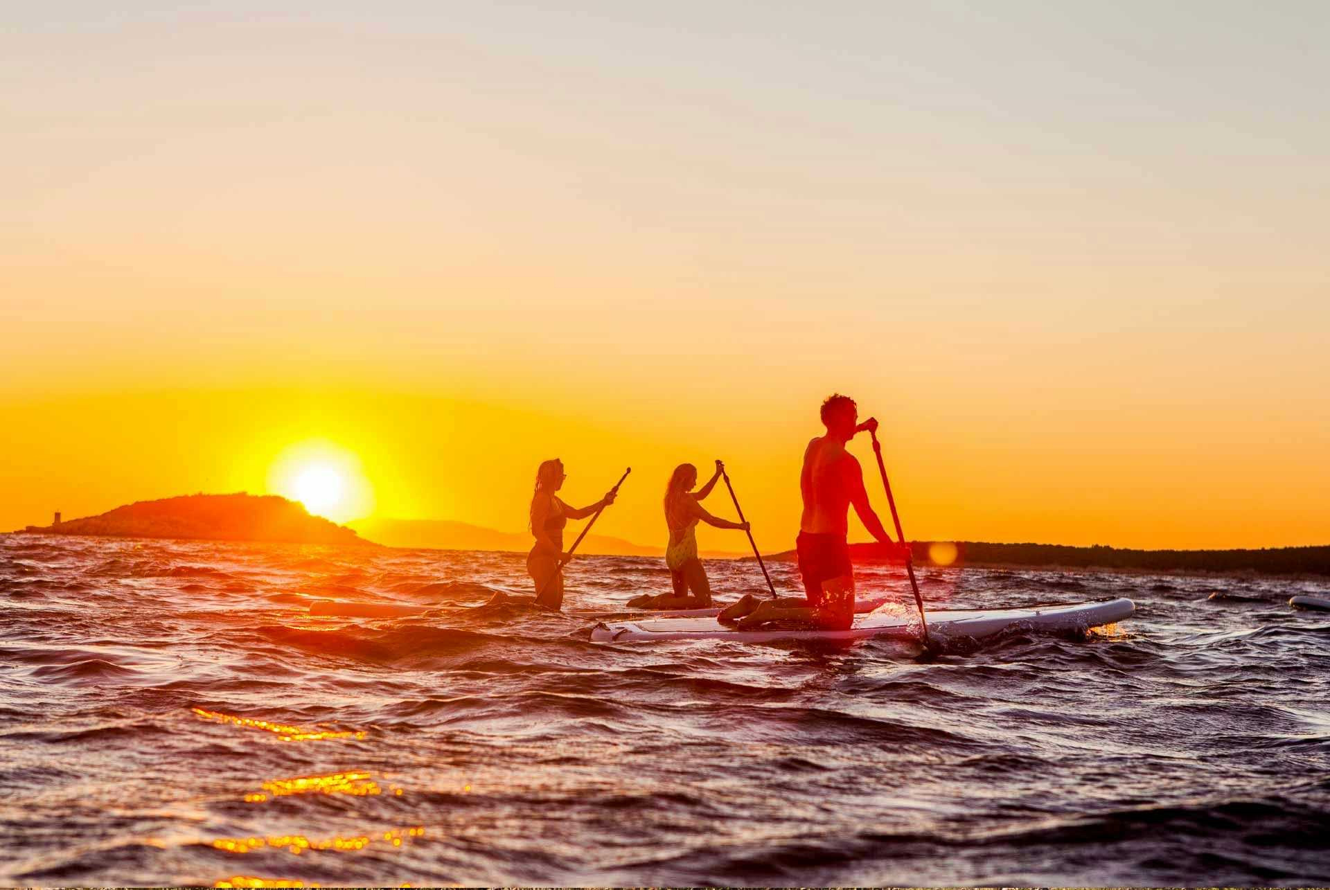 Friends paddleboarding at sunset