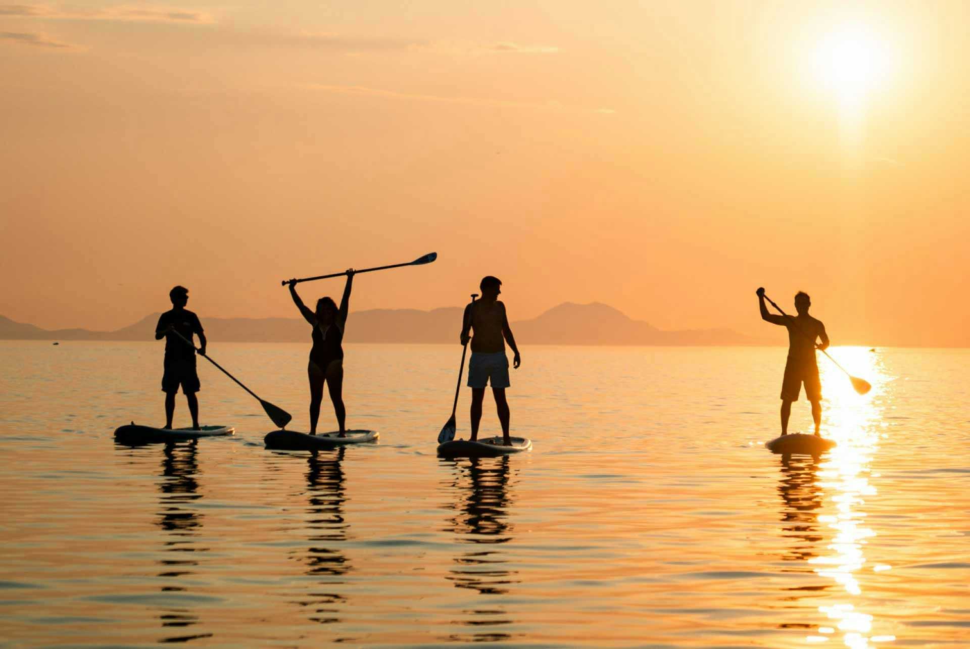 Group of people paddleboarding at sunset