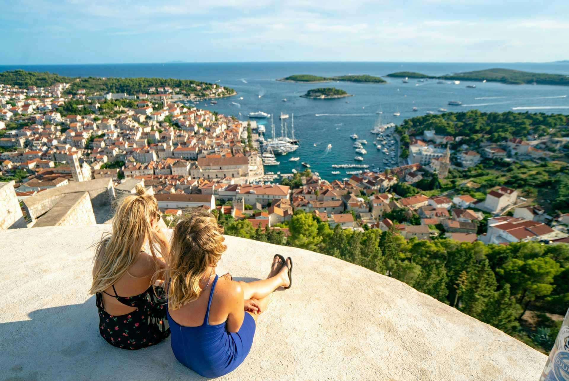 Two women sit looking at the view over Hvar from Hvar fortress
